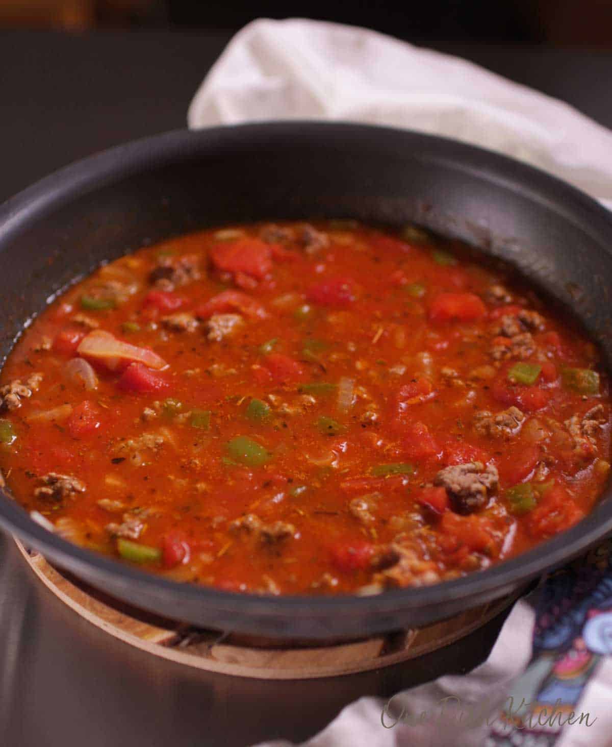 Ground beef, onions, green bell peppers, and garlic simmering in a tomato sauce for american goulash.