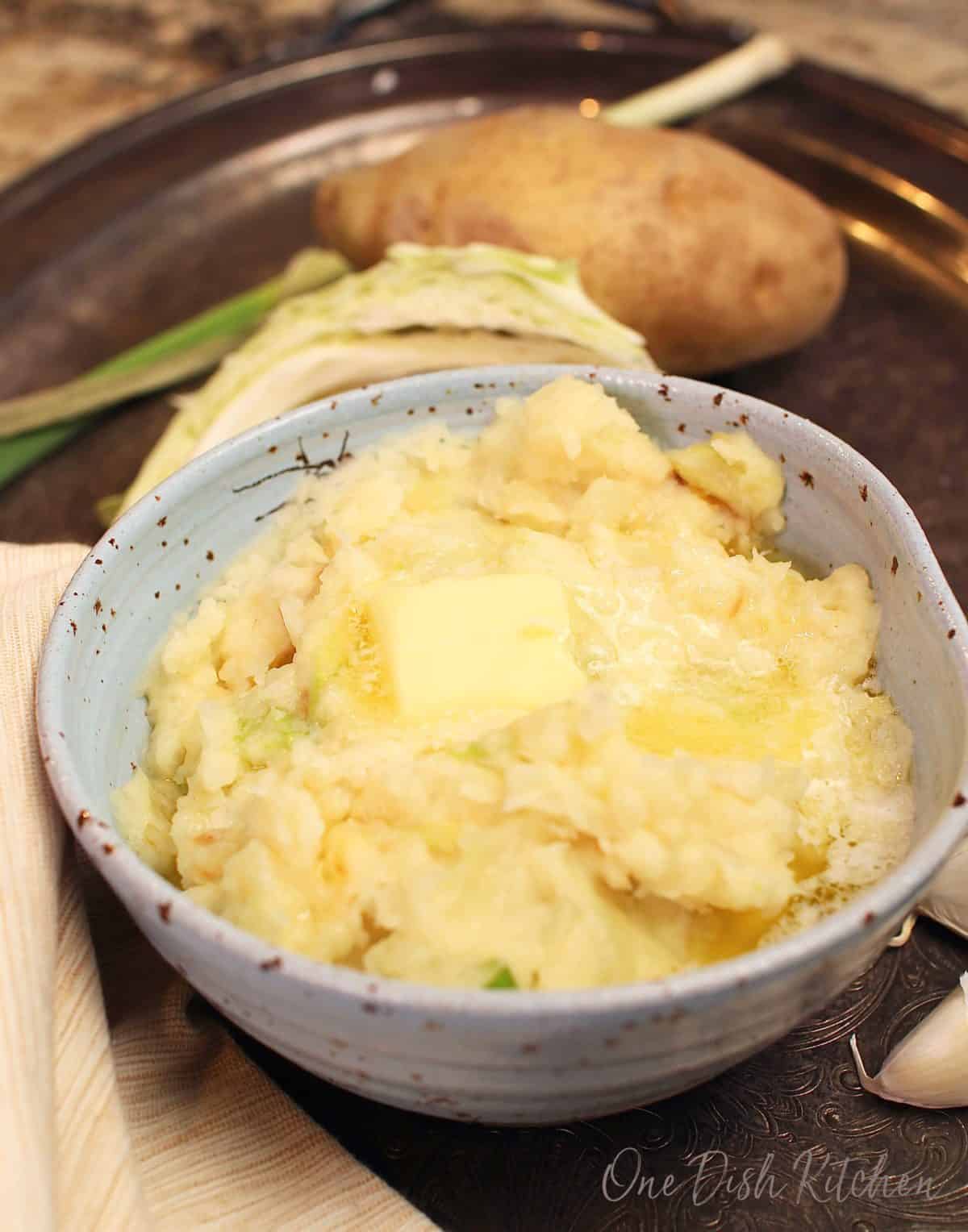 a blue bowl of colcannon with butter melting on the top.