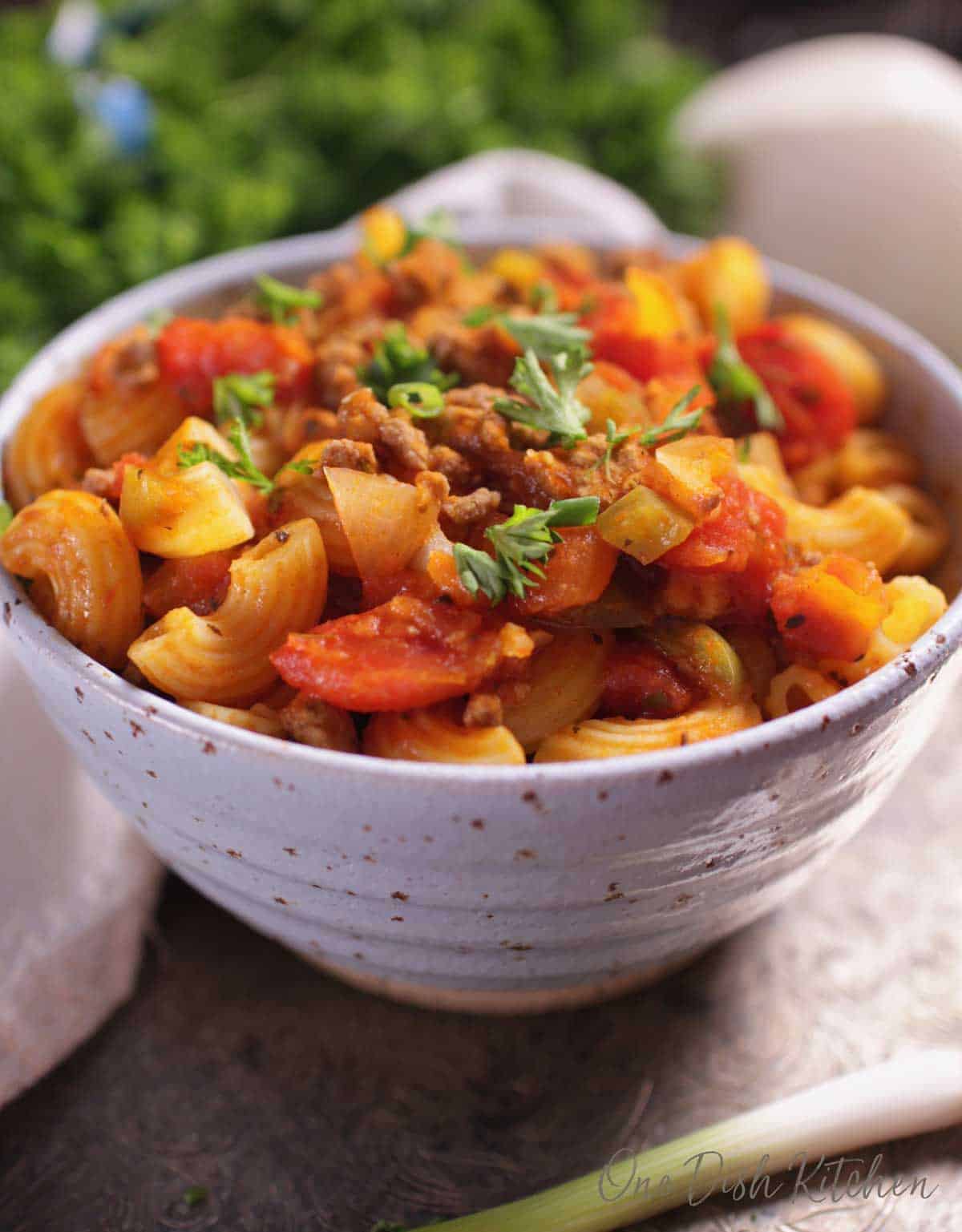 A bowl of american goulash topped with fresh parsley.
