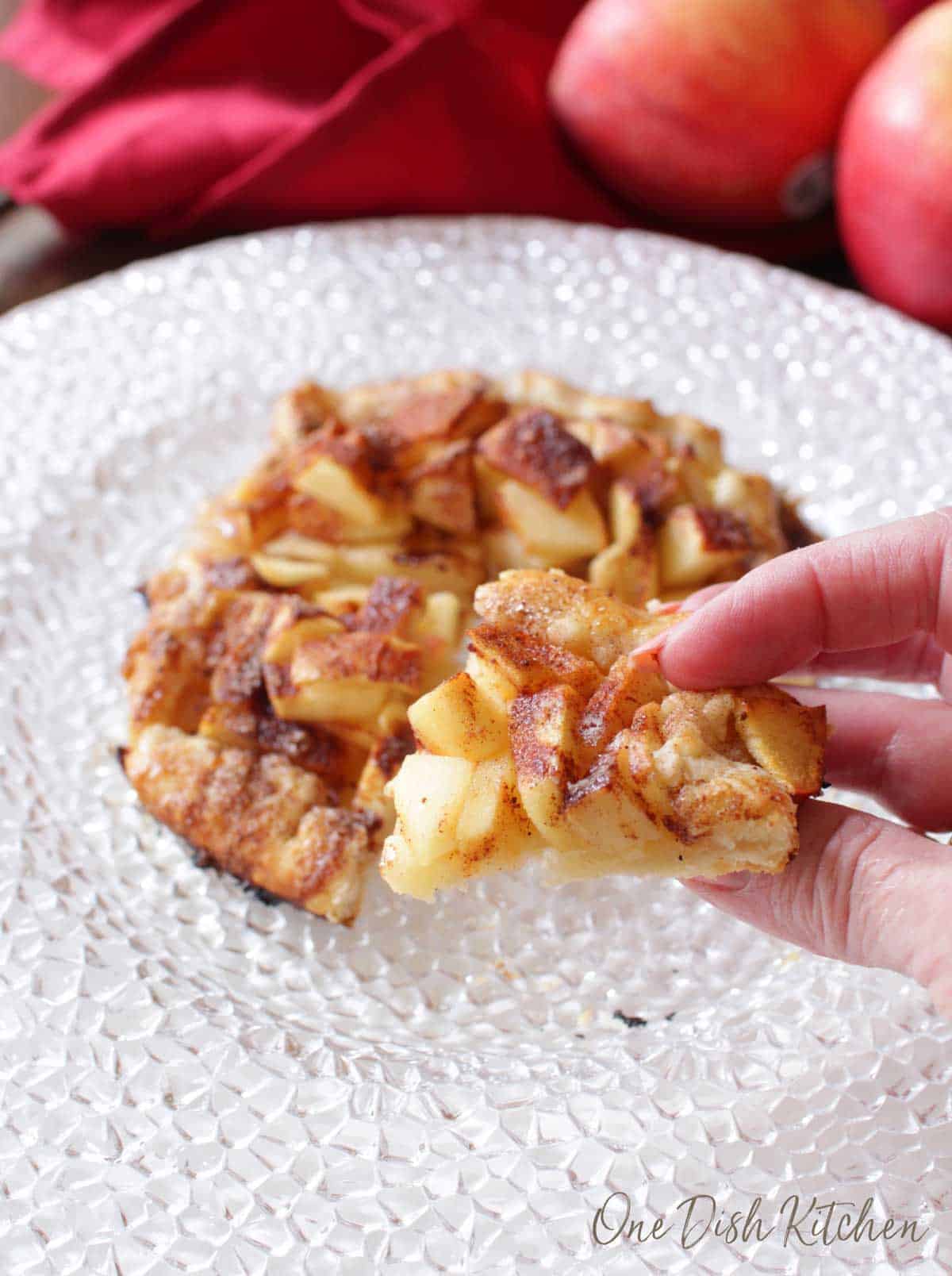 A closeup of fingers holding a piece of an apple galette