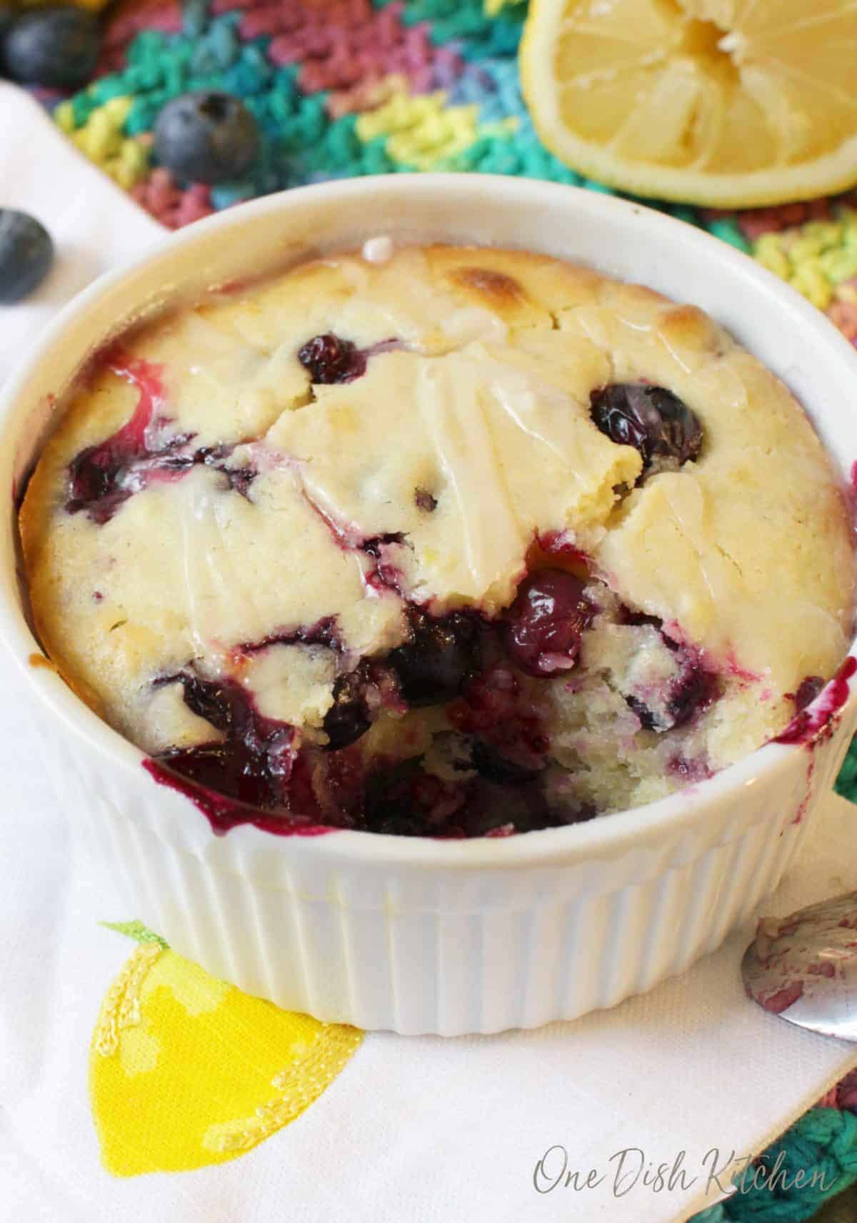 A closeup of a spoonful missing of lemon blueberry muffin filled with blueberries and a sugar lemon glaze.