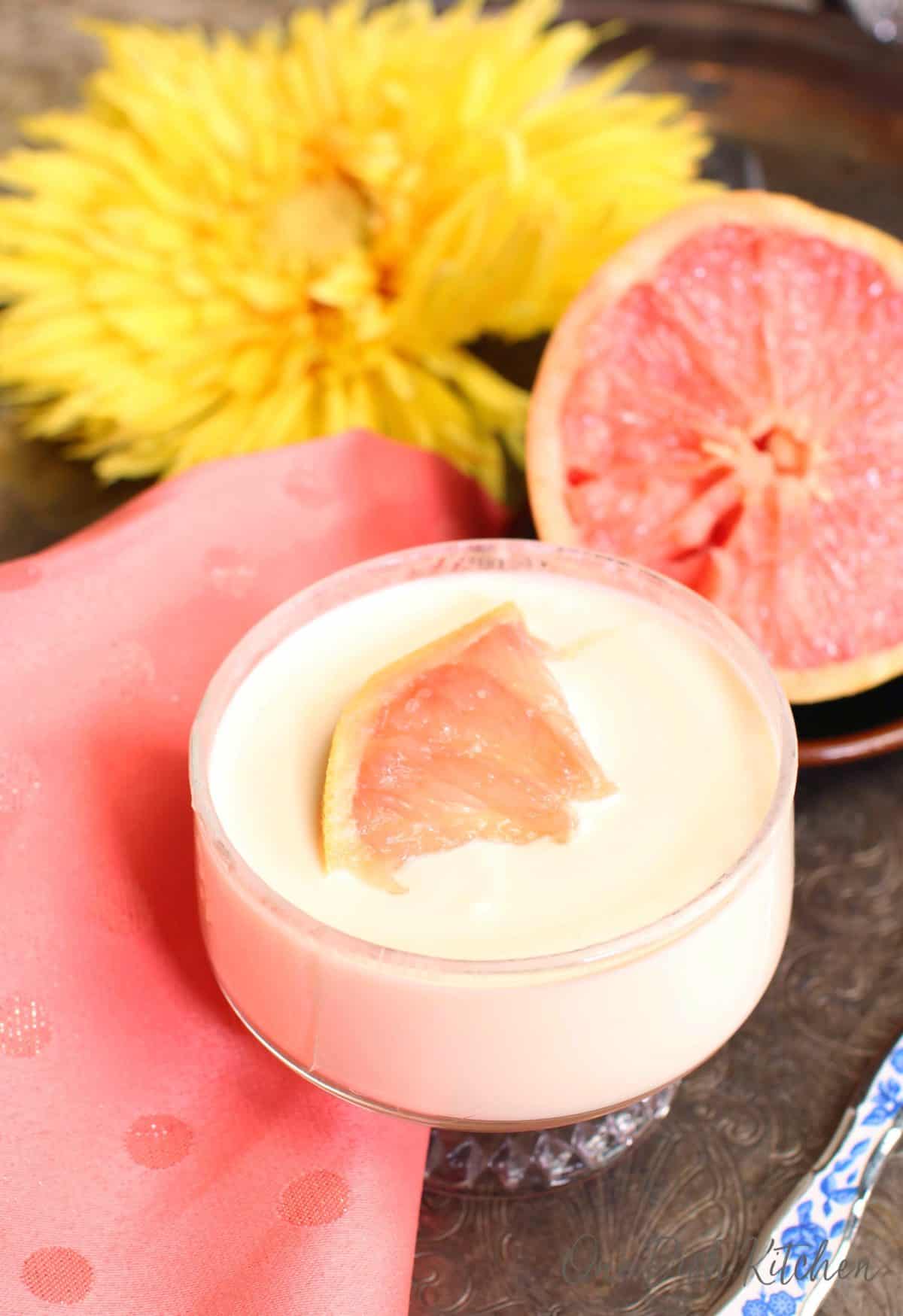 a pudding topped with a grapefruit segment in a clear dessert bowl