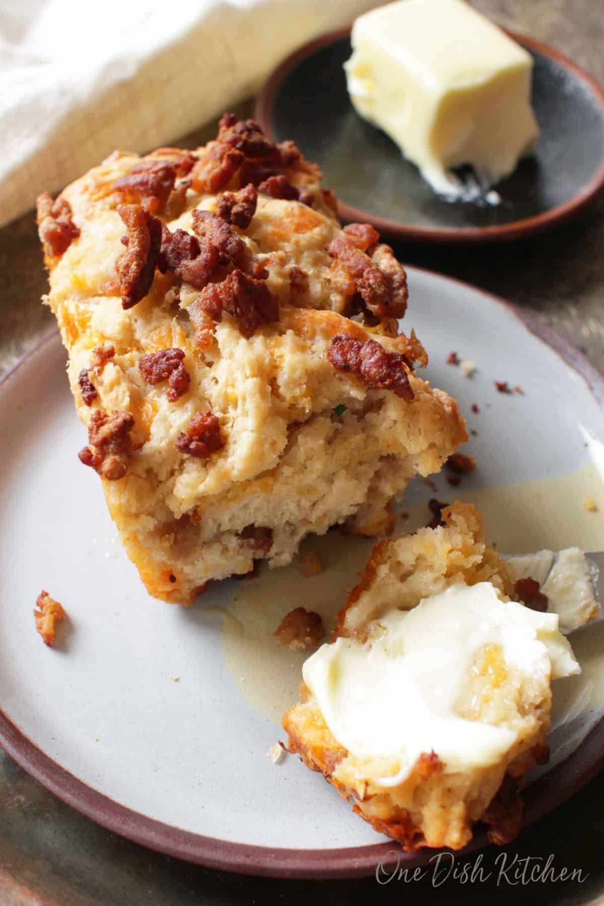 Spreading butter over a slice of sausage beer bread.