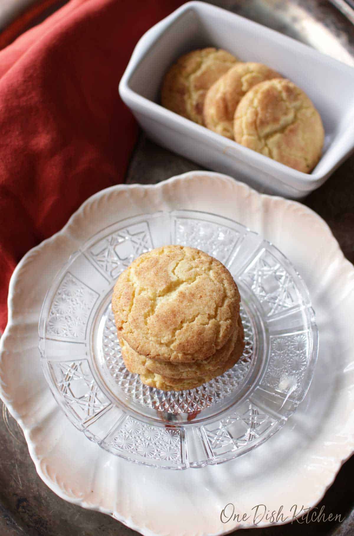An overhead view of three snickerdoodle cookies on a plate next to a row of cookies in a loaf pan