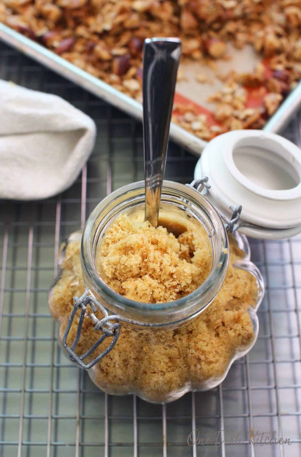 an overhead view of an open jar of brown sugar next to a tray of granola.