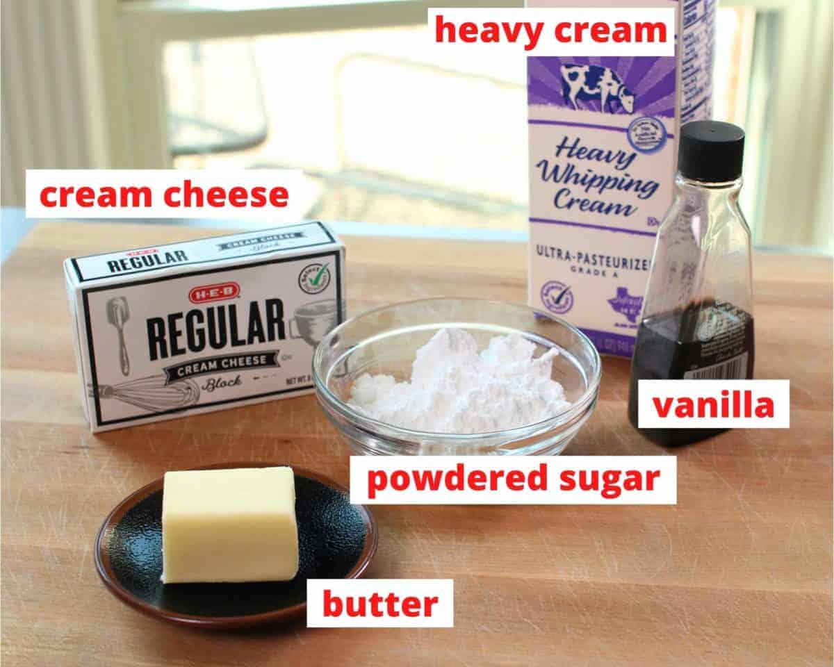 ingredients needed for frosting labeled and on a brown table next to a window.
