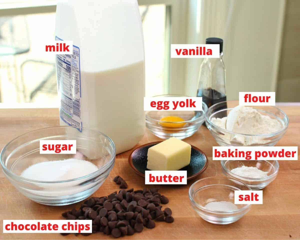 the ingredients needed to make a chocolate chip muffin labeled on a table.