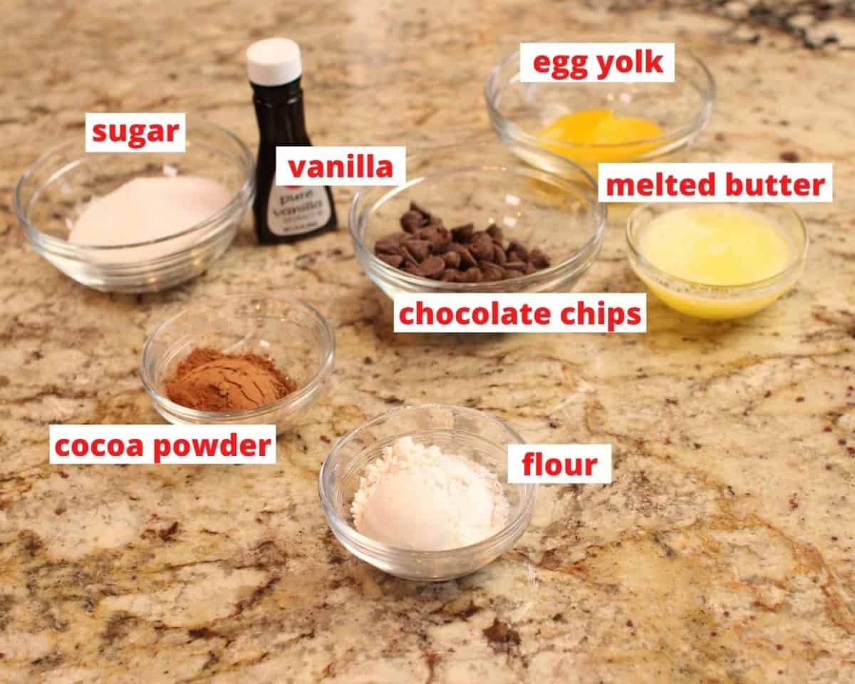 flour, chocolate chips, cocoa powder, butter, vanilla, and egg in individual bowl on a granite countertop