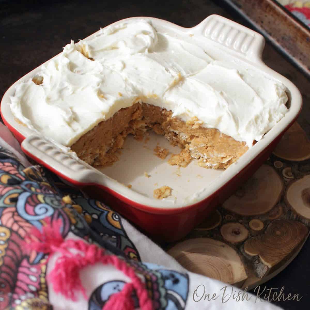 a red baking dish filled with peanut butter bars and one square cut out.