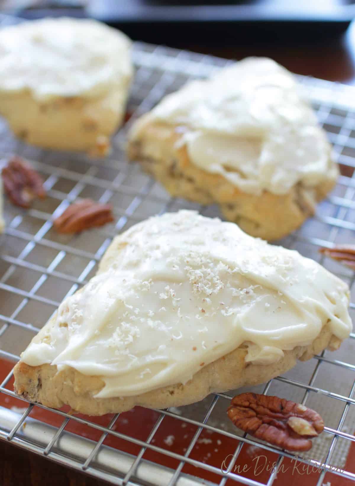 three frosted scones on a cooling rack