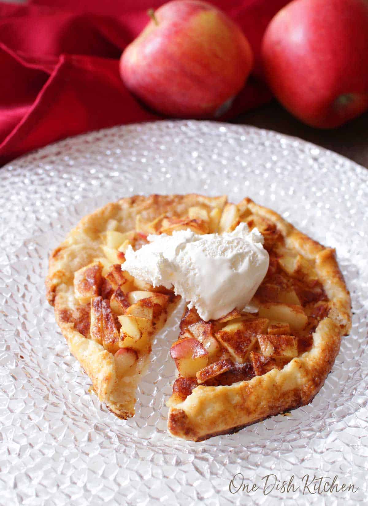 An apple galette topped with whipped cream cut into four slices