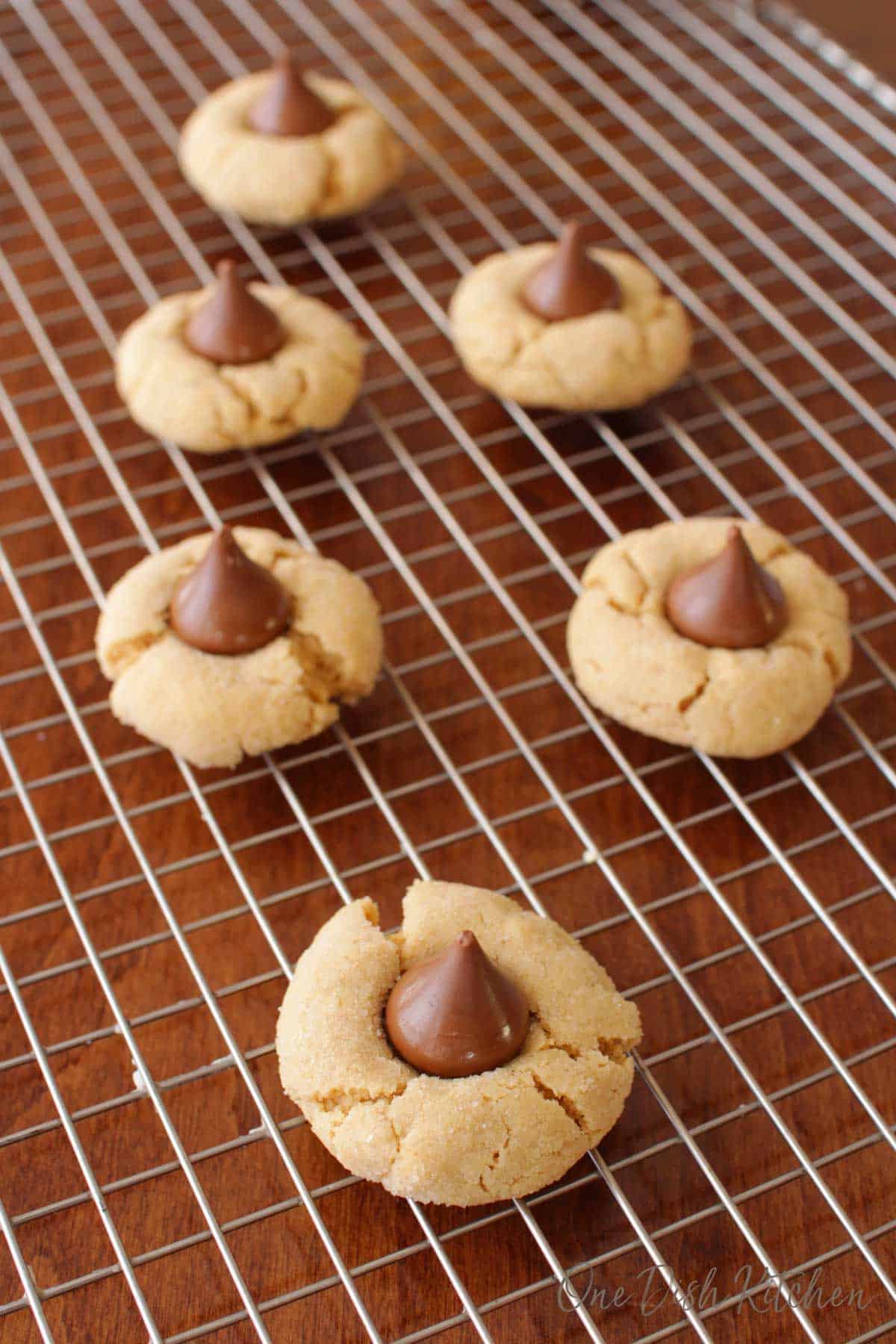 Six peanut butter kiss cookies on a cooling rack