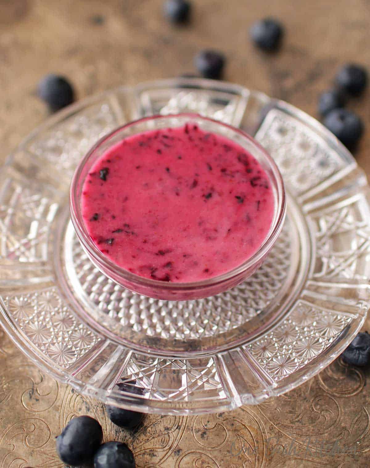 Salad dressing made with blueberries in a small bowl on a tray