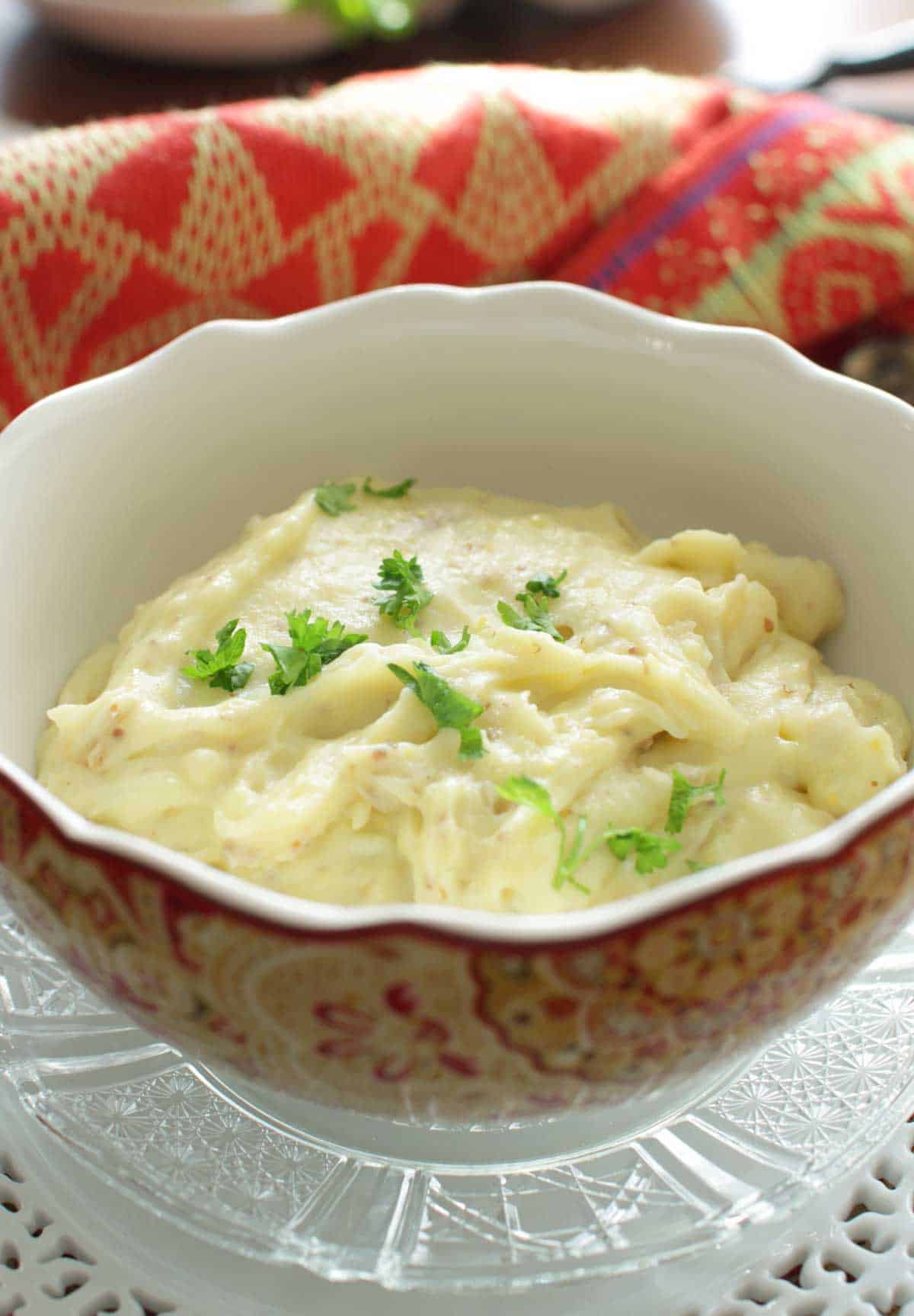 A closeup of a bowl of mashed potatoes topped with parsley