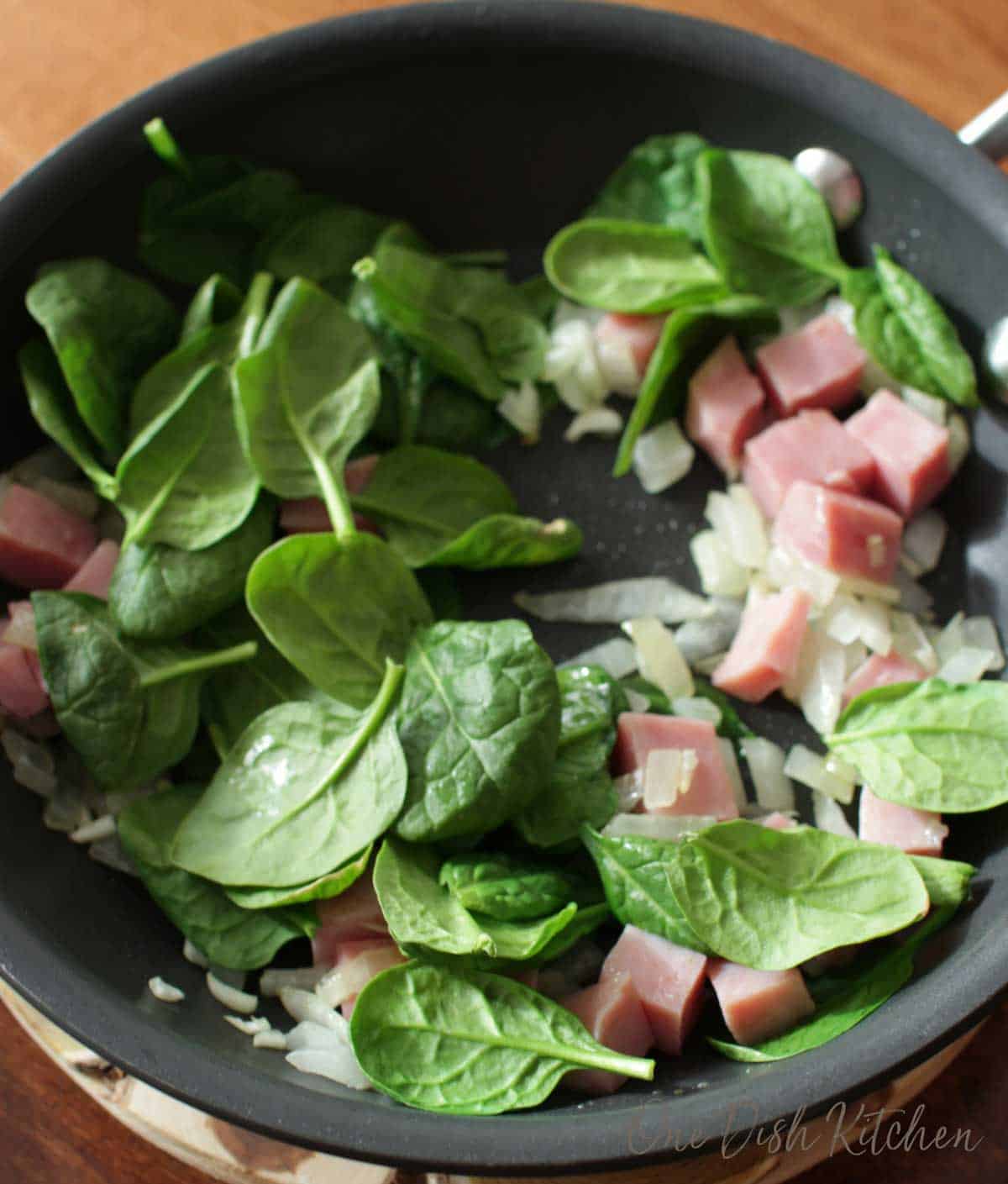 Spinach, onions, and diced ham in a skillet
