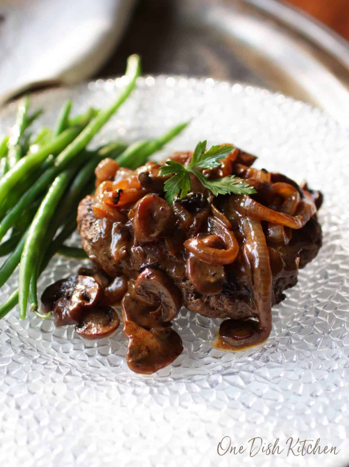 Salisbury steak on a plate next to green beans