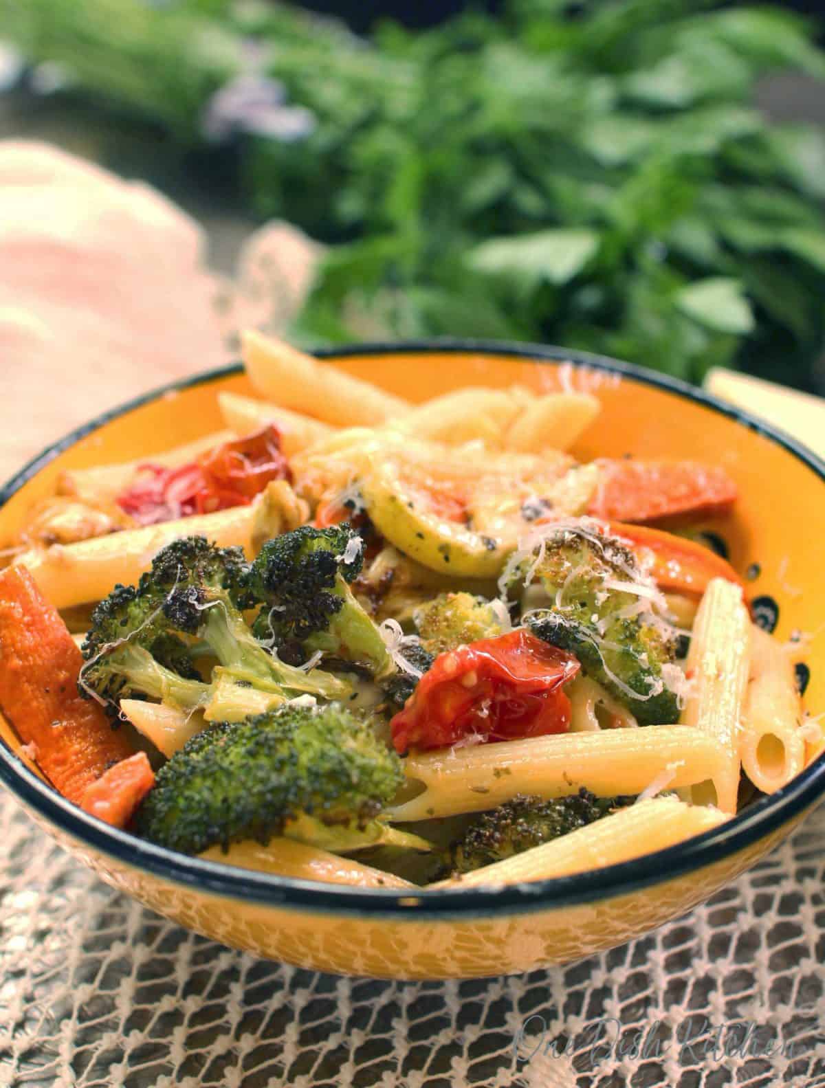 a bowl of pasta primavera on a lace placemat next to parsley.