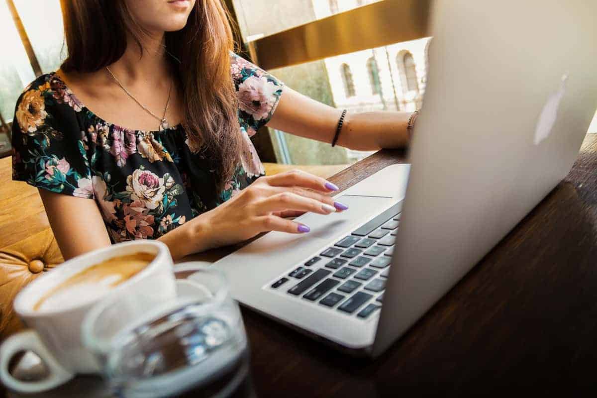 woman working on laptop near window with cup of coffee
