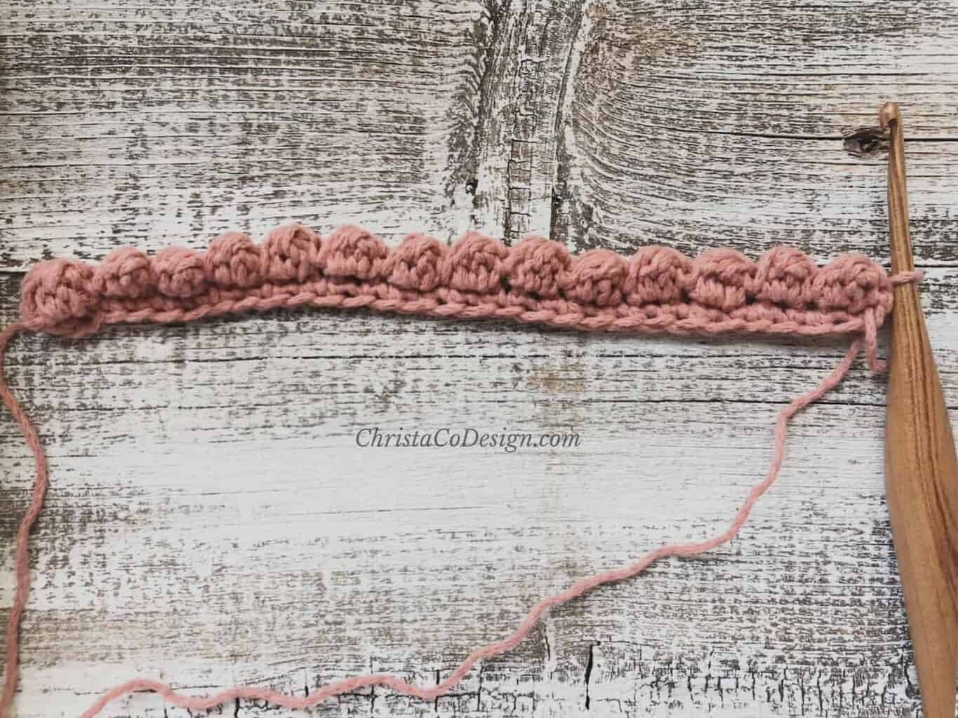 picture of row 2 uneven berry stitch tutorial in pink yarn