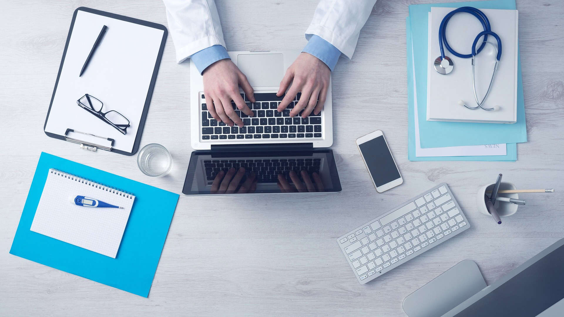 doctors hands at a desk with laptop and note books