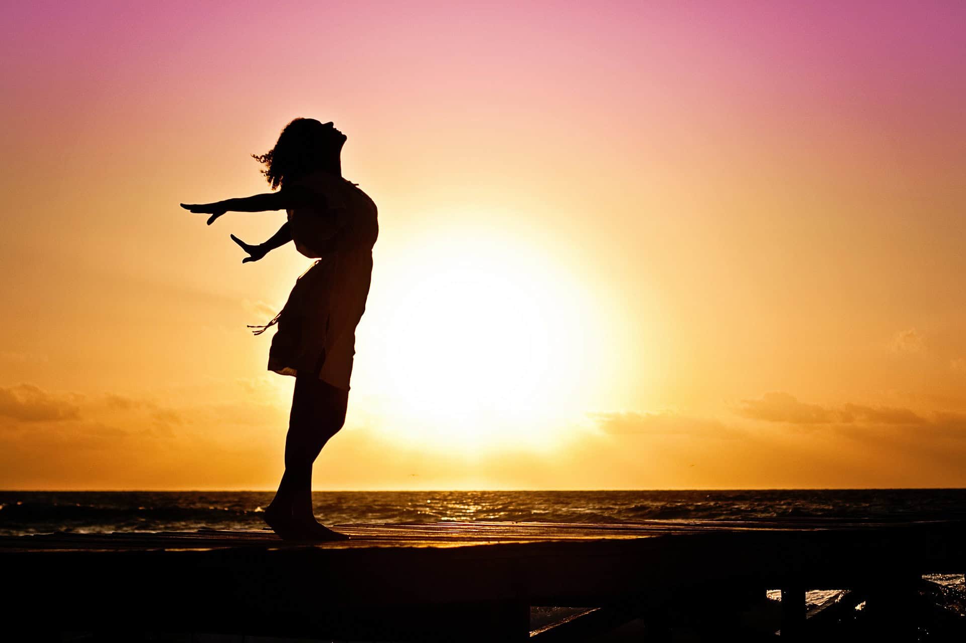 woman at sunset putting her hands back