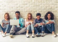 group of friends each on a laptop, tablet or phone playing online casino games