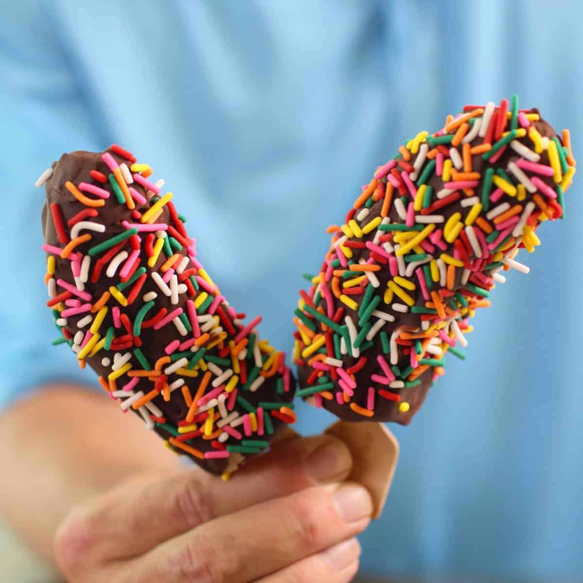 two halves of a chocolate covered banana on popsicle sticks.
