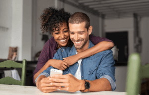 landlord mobile app image: woman hugging man and smiling over his shoulder as he looks at phone