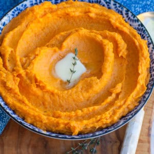 butter and thyme mashed sweet potatoes in blue bowl with butter