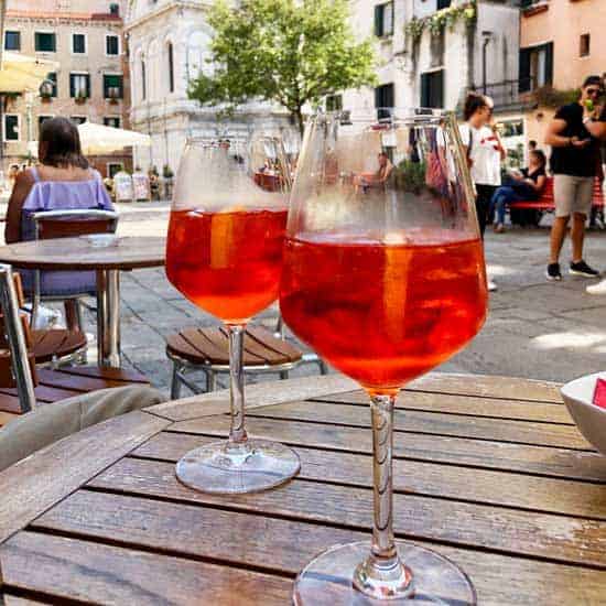 two glasses of Aperol Spritz on a wood table