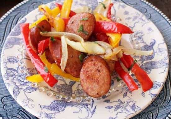 Roasted sausage, red and yellow peppers and onions in a white and blue bowl