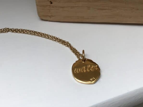 the reverse side of the necklace which has water inscribed on it