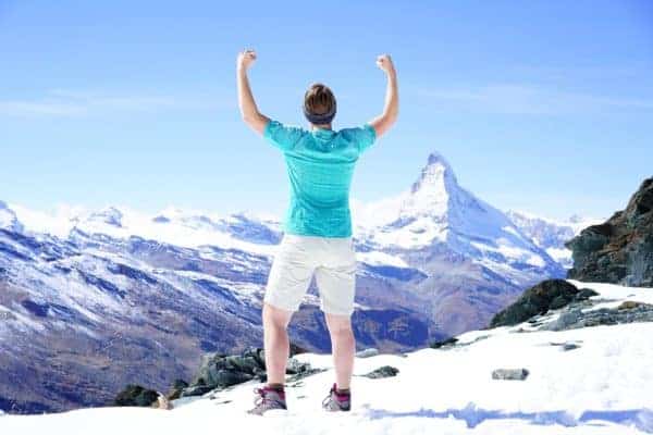 A person exulting in their hiking victory in sight of the matterhorn.