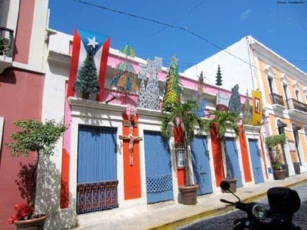 A typical street in old san juan with brightly colored houses and christmas type decorations.