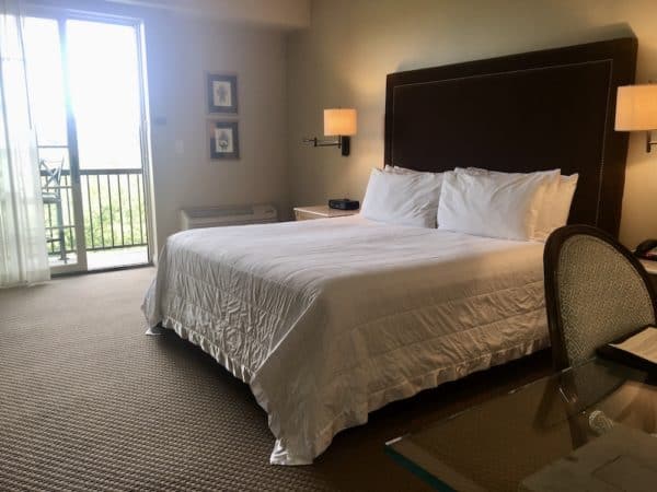 The queen rooms at the Diamond Mills Hotel in upstate NY has brown and beige tones and doors that lead to a balcony and views of the creek.