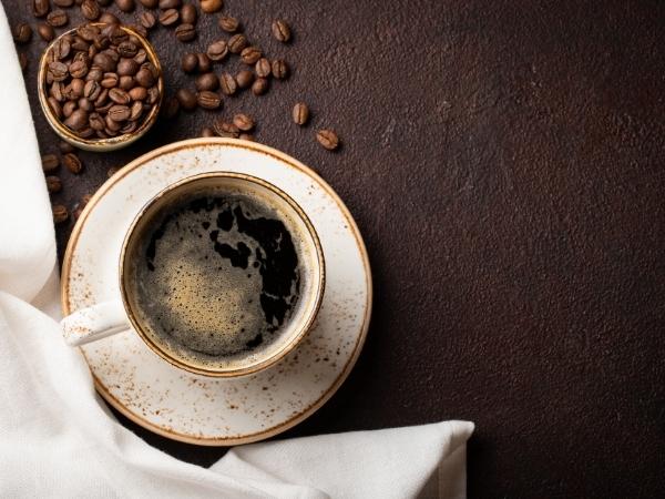 black coffee in a cup with coffee beans on the table