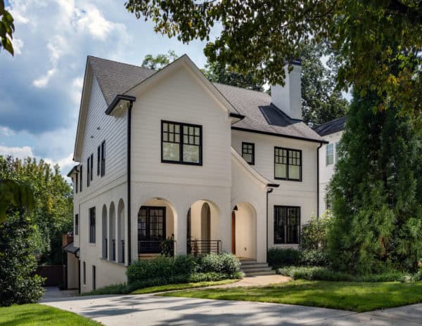 a large tudor house painted in white and decorative black wood windows