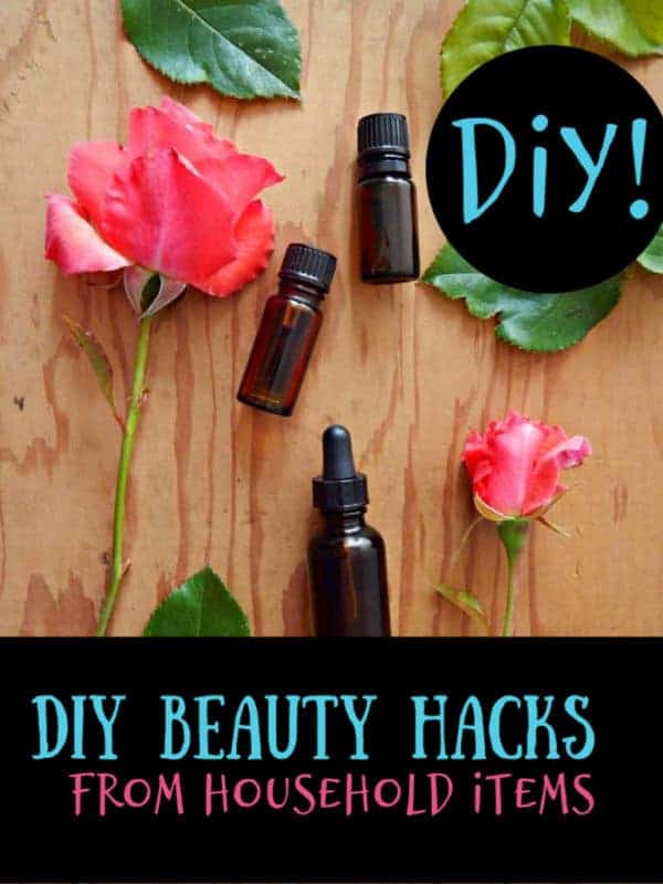 essential oil bottles on a wood board with roses laying next to them.