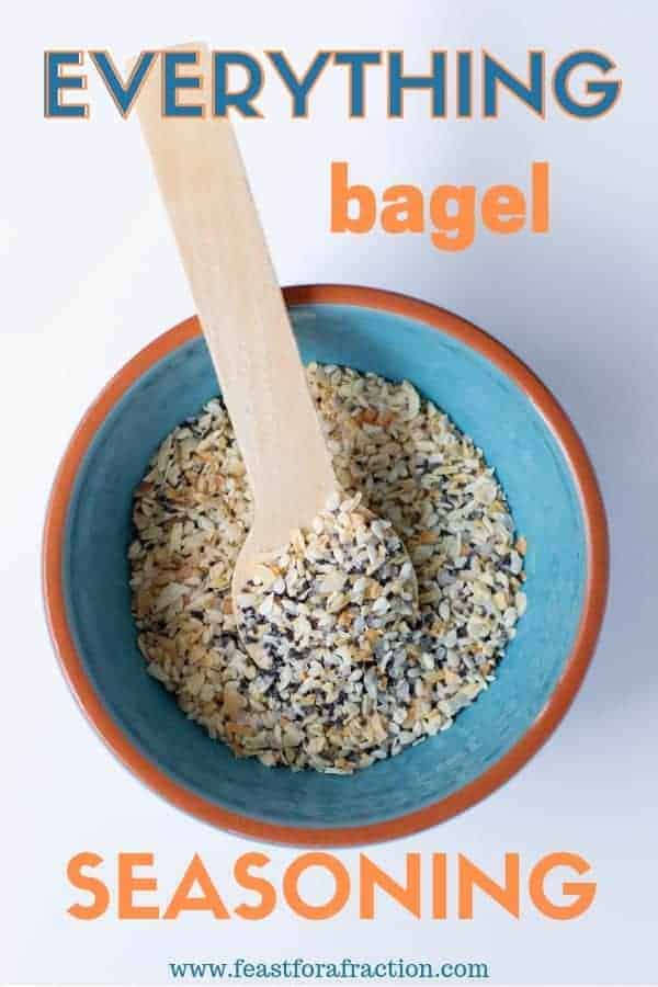 everything bagel seasoning in a teal bowl with a wooden spoon sitting on a white background