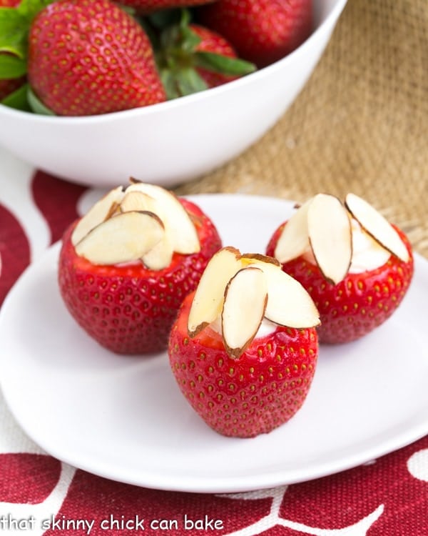 Cheesecake Stuffed Strawberries - An easy, irresistible sweet treat! Perfect healthier option for a dessert buffet! Cheesecake Stuffed Strawberries on a small oval plate topped with sliced almonds
