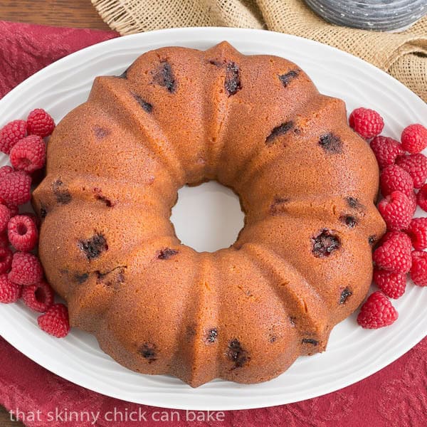 Raspberry Amaretto Bundt Cake - Pound cake full of fresh raspberries and flavored with extracts and liqueur Overhead view of Raspberry Amaretto Bundt Cake on a white, oval platter