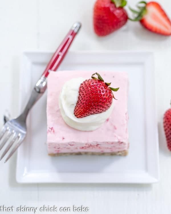 Strawberry Pie Dessert - A dreamy frozen strawberry fluff dessert! Overhead view of a slice of Strawberry Pie Dessert on a square white plate with a red handled fork