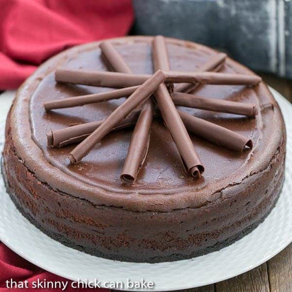 Triple Chocolate Cheesecake - A dreamy, chocolate lover's dessert! Triple Chocolate Cheesecake on a white ceramic plate topped with chocolate curls