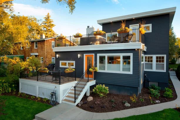 a contemporary exterior with dark-charcoal painted siding, white trim, and bright orange door