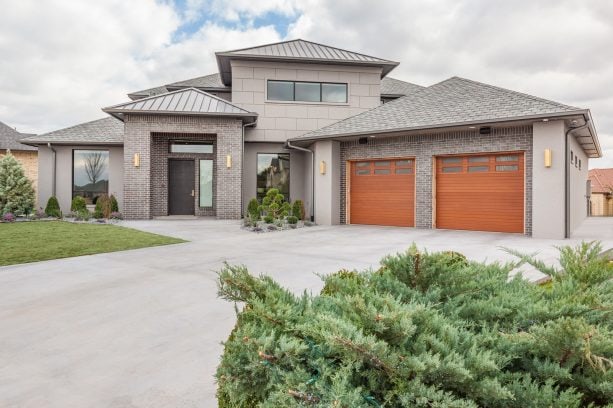 a grey stucco and brick house with bronze metal roof