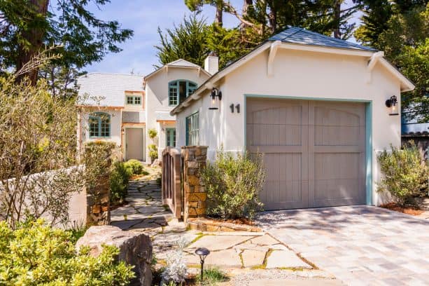 a beautiful, humble, and timeless detached garage in front of a traditional house