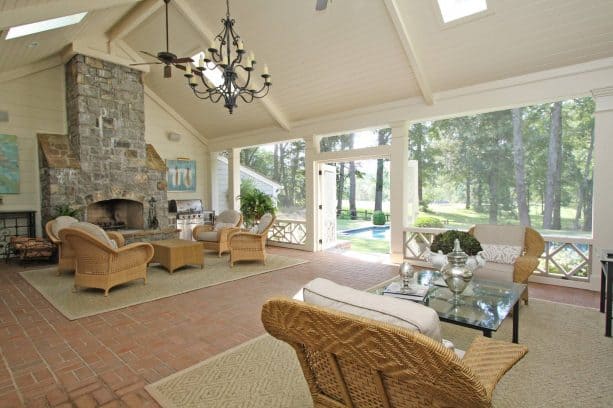 a spacious, luxurious traditional screened porch with large stone fireplace