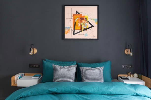 bed with teal bedding set placed in front of a muted black wall