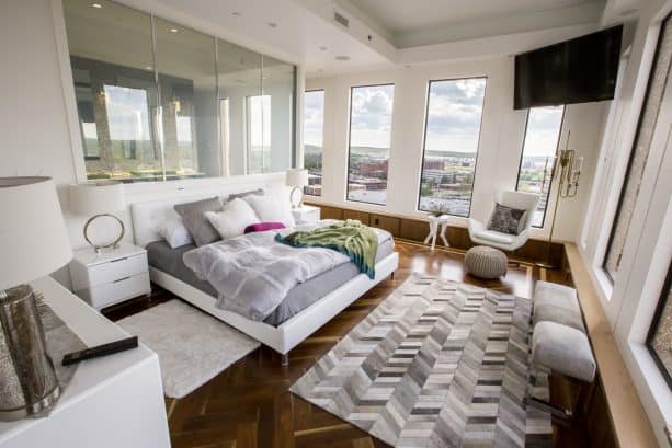 a grey and white bedroom with glossy dark hardwood floor