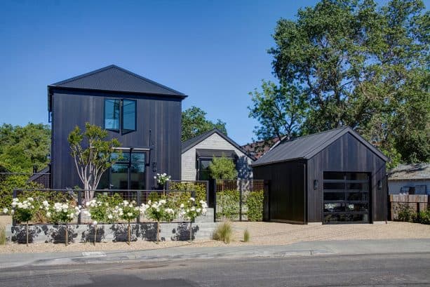 a front-load garage located in front of a black contemporary-farmhouse residence